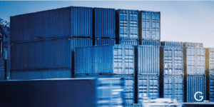 Stacked shipping containers in a logistics hub with a blurred motion of a truck passing by, symbolizing global trade, freight transportation, and supply chain management.